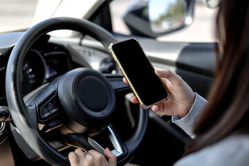 Close-ups of women holding the steering wheel and using mobile phone while driving, using the phone while driving is dangerous and illegal, the concept of safe driving.