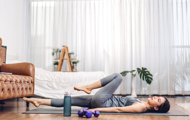 Portrait of sport asian woman in sportswear sitting relax and practicing yoga and do fitness exercise in bedroom at home.Diet concept.Fitness and healthy lifestyle