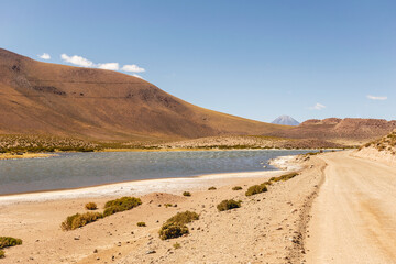 Fototapeta na wymiar Desert road with lake and mountain