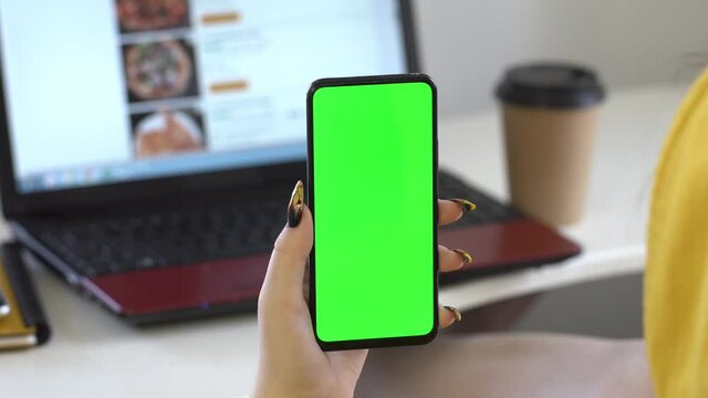 Business woman using smartphone viewing green screen on mobile phone browsing chroma key online watching enjoying drinking coffee close up hands