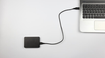 External hard drive connected to laptop on white surface. Concept for office, business, education and presentation