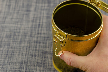 A man's hand holding an open Tea Coffee tin with a clasp close-up.