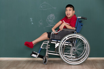 Fototapeta na wymiar Asian disabled boy on wheelchair showing his painting on wall with happy and proud. Idea for learning ability of handicapped kid.