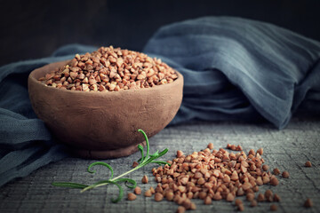 Buckwheat in a clay plate on a wooden background.Healthy food.