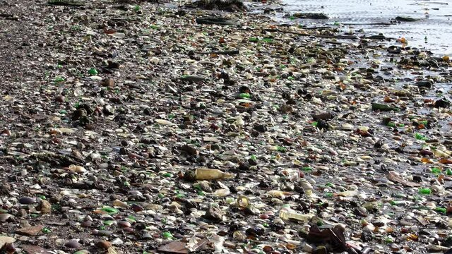Extremely polluted Beach on Atlantic Ocean. Trash, Rubbish and waste covering sand on beach. Glass peaces polluting beautiful Beach. Recycle failure