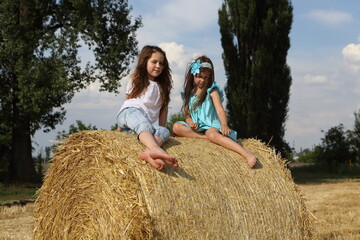 Naklejka na ściany i meble Two little girls playing in a wheat field