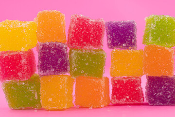 closed up lot of colorful cube jelly candy roll on pink background