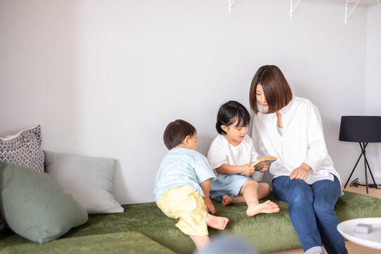 リビングのソファで母親と子供が本を読んでいる　kids book mother
