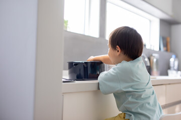 白いキッチンで男の子が青い鍋で料理をしている　boy kitchen 