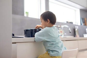 白いキッチンで男の子が青い鍋で料理をしている　boy kitchen 