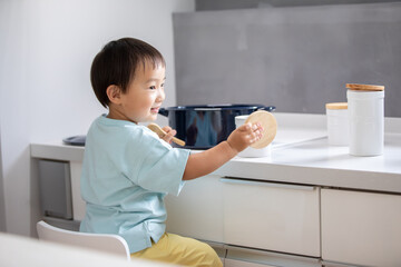 白いキッチンで男の子が青い鍋で料理をしている　boy kitchen 