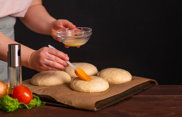 The chef prepares the burger buns for baking by brushing them over with yolk. Cooking a burger.