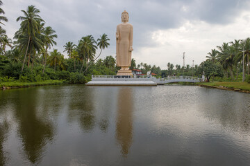 Giant standing Buddha sculpture on the Tsunami Honganji Vihara on a cloudy evening, Peralia. Sri Lanka