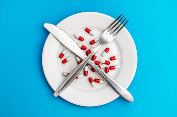 Red-white pills on the plate with fork and knife. Diet. Healthy lifestyles.