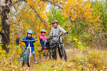 Plakat Family cycling in golden autumn park, active father and kids ride bikes, family sport and fitness with children outdoors 