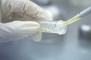 Asia scientist wears a glove used a micropipette and transfer sample into a tube in the biosafety...