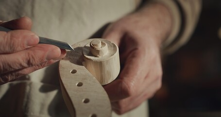 Cinematic macro of experienced master artisan luthier painstaking detail work on fine quality wood violin in creative workshop.Concept of spiritual instrument,handmade, art, orchestra, artisan,passion - obrazy, fototapety, plakaty
