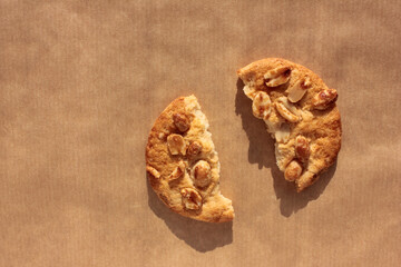 Piece of peanut cookie on kraft paper. Close-up of homemade pastry on brown background with copy space
