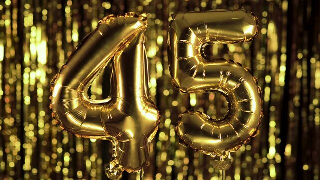 The golden number 45 forty five is made of an inflatable ball on a yellow background. One of the complete set of numbers. Birthday, anniversary, date concept