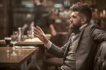 Confident bar customer speak in cafe. Date or business meeting of hipster in pub. Bearded man in restaurant.