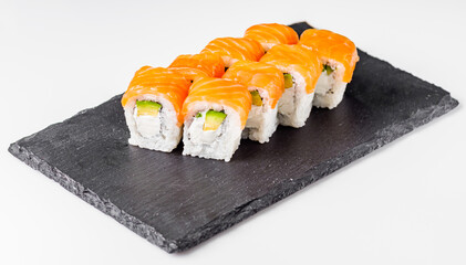 appetizing philadelphia sushi roll with salmon and avocado on a black stone plate
