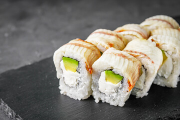 appetizing Philadelphia sushi roll with eel and avocado on a black stone plate