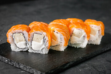 appetizing sushi roll philadelphia with tofu and salmon on a black stone plate