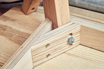 Corner of upside-down stylish new table of plywood, veneer and solid light ash in modern carpentry workshop extreme close view