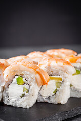 appetizing sushi roll philadelphia with avocado cheese cucumber and shrimp on a black stone plate