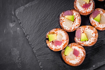 appetizing sushi roll with tuna salmon escolar crab and avocado on a black stone plate