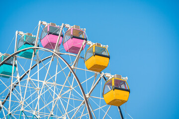 Colorful ferris wheel in an amusement park against blue sky