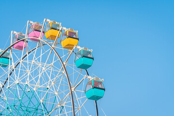 Colorful ferris wheel in an amusement park against blue sky