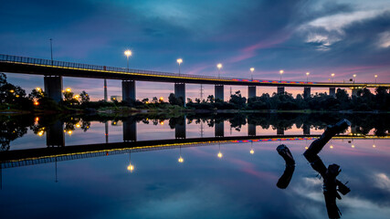 The reflections of the melbourne city skyline at dusk in the still water of the west gate bridge