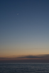 静かな海の夕暮れと三日月
