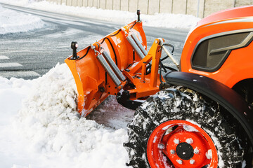 The tractor cleans the sidewalk in the winter in January