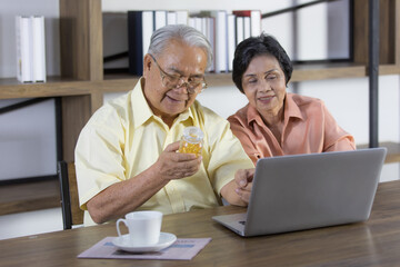 Senior man and woman lover sitting together and using laptop notebook computer to search for details and benefits of drugs on internet search engine