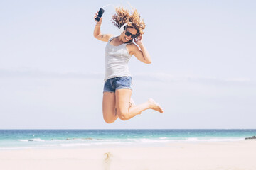 Happy young adult caucasian woman jump and have fun at tghe beach in alone free summer holiday...