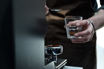 Detail of hand, glass and freshly roasted coffee.