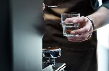 Detail of hand, glass and freshly roasted coffee.