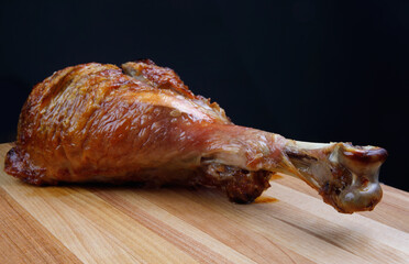 Baked turkey shin on a wooden cutting board.