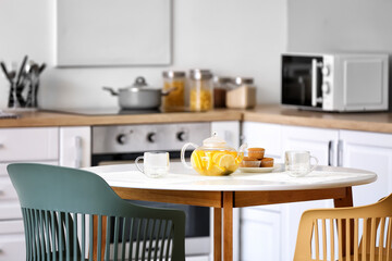 Teapot with hot healthy beverage on table in kitchen