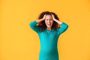 Stressed pregnant African-American woman on color background