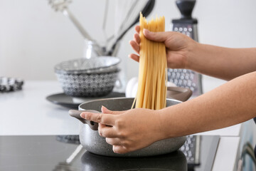 Woman cooking tasty pasta in kitchen