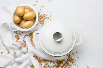 Potatoes, lentils and cooking pot on light background