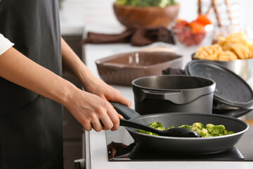 Woman cooking broccoli in kitchen