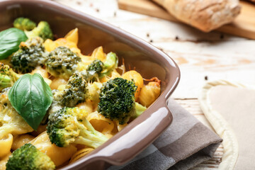 Tasty baked pasta with broccoli and cheese in baking dish on table, closeup