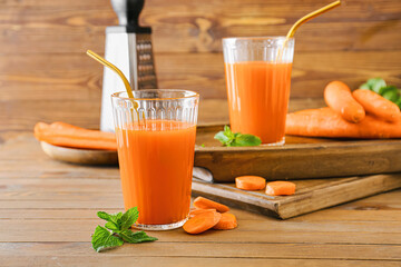 Glasses of tasty carrot juice on wooden table