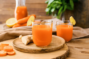 Plate with glass of tasty carrot juice on blurred background