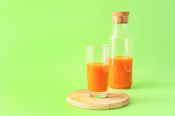 Glass of tasty carrot juice on color background