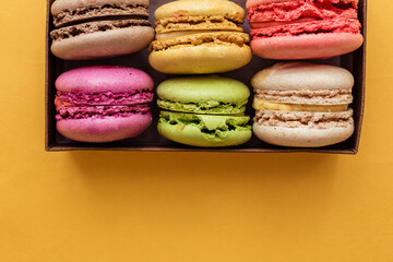 Colorful macaroons. Sweet pasta on a yellow background with copy space. Top view, holiday time concept